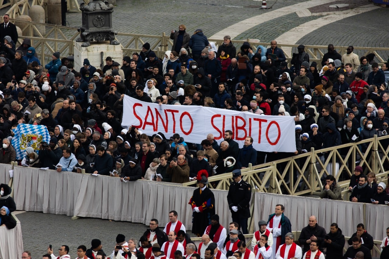 Fieles muestras un letrero con la leyenda Santo súbito durante la Misa de exequias del Papa emérito Benedicto XVI / Foto: Maria Langarica